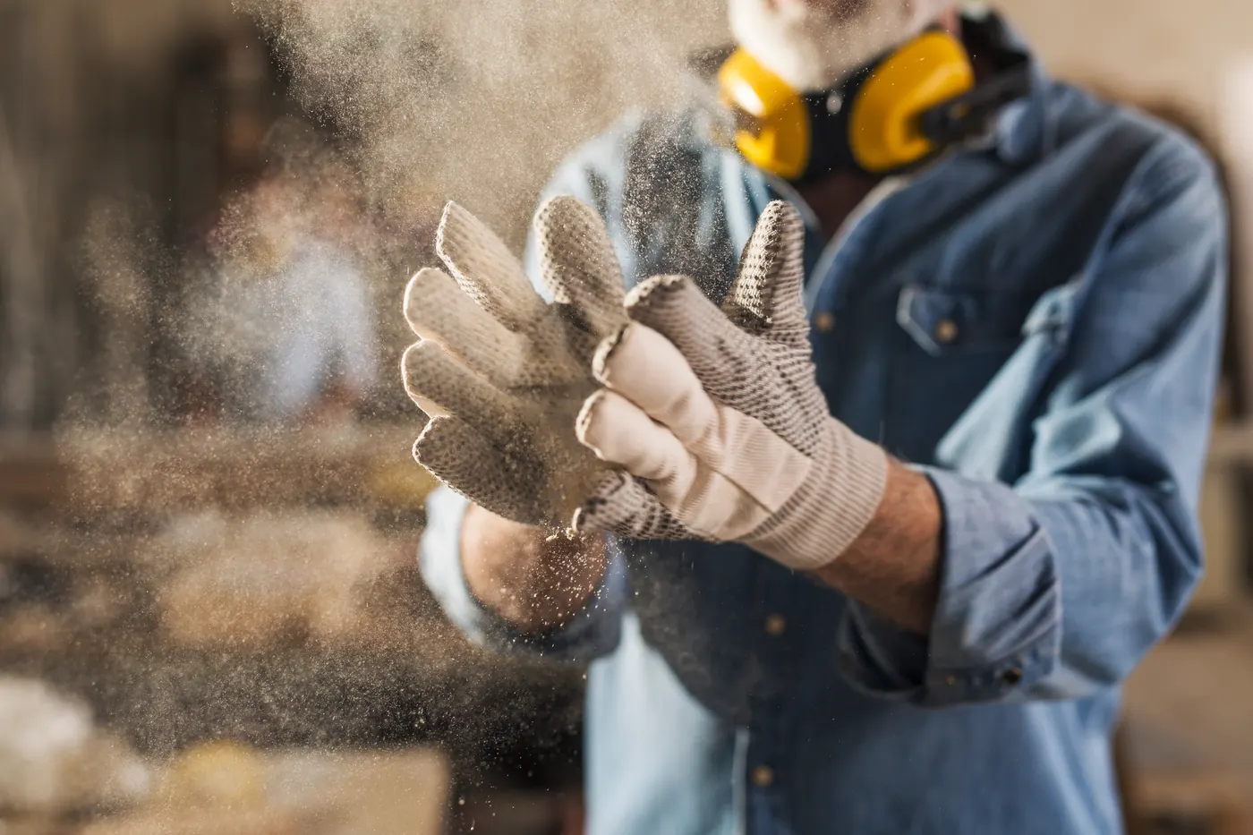 Handwerker klopft Staub von seinen Arbeitshandschuhen